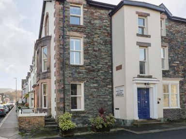 A street view of stone and plaster residential buildings with blue door at Carlton House Apartment 1 in Keswick