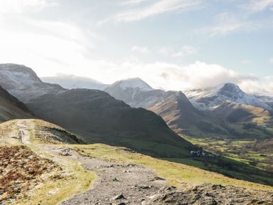 A mountainous landscape with a dirt path and snow-capped peaks at Carlton House Apartment 1 in Keswick