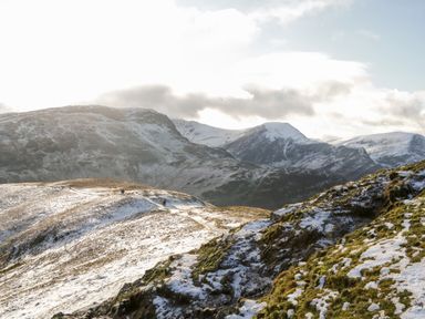 A mountain landscape with patches of snow and a cloudy sky at Carlton House Apartment 1 in Keswick