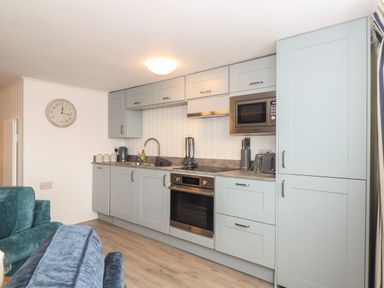 A kitchen with gray cabinets a built-in oven microwave toaster and sink in Harbour Studio in Sennen Cove