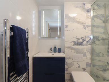 A bathroom with a sink cabinet mirror towel rail toilet and shower at Harbour Studio in Sennen Cove