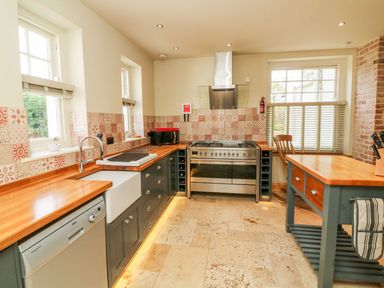 A kitchen with wooden countertops a farmhouse sink a stainless steel oven and a kitchen island at Westholme Lodge in Minehead