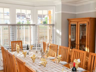 A dining room with a wooden table set with wine bottles glasses napkins and candlesticks at Westholme Lodge in Minehead