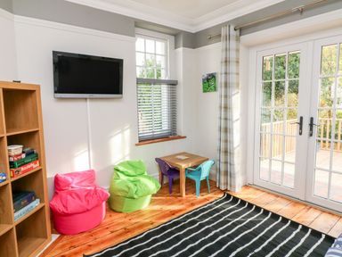 A playroom with bean bag chairs a small table with two chairs a wall-mounted TV and a bookshelf at Westholme Lodge Minehead