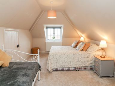 A bedroom with a bed and side table with lamps under a sloped ceiling at Westholme Lodge in Minehead