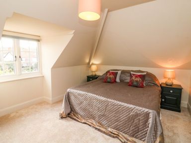 A bedroom with a bed, two nightstands with lamps, and a window under a sloped ceiling at Westholme Lodge Minehead