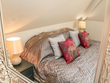 A bedroom with a bed featuring quilted bedding pillows with stag designs and two bedside tables with lamps at Westholme Lodge in Minehead