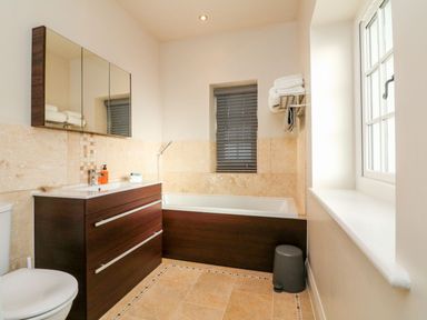 A bathroom with a bathtub vanity mirror toilet and window at Westholme Lodge in Minehead