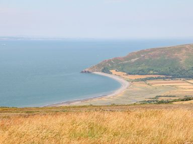 A coastal landscape with a curved beach fields and hills at Westholme Lodge in Minehead