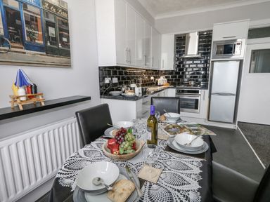 A kitchen with a dining table set for four with bowls plates and a fruit bowl at Sunbeach in Weymouth