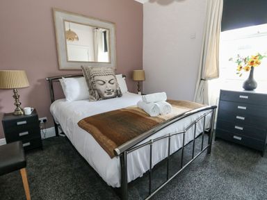 A bedroom with a metal bed frame white bedding and a pillow with a face design at Sunbeach Weymouth