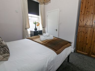 A bedroom with a bed with towels on it a wardrobe and a window with curtains at Sunbeach in Weymouth