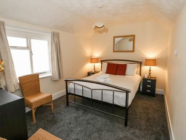 A bedroom with a bed bedside tables lamps a mirror two chairs and a window at Sunbeach Weymouth