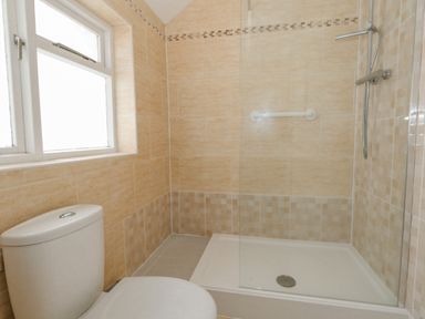 A bathroom with a toilet and a walk-in shower with beige tiles at Sunbeach Weymouth