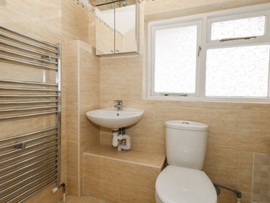 A bathroom with a toilet sink a mirrored cabinet a window and a heated towel rail at Sunbeach in Weymouth