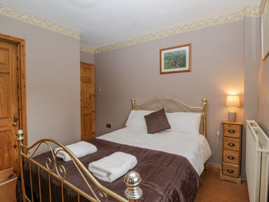 A bedroom with a metal bed frame brown bedding and two wooden doors at Field Cottage in Shepton Mallet