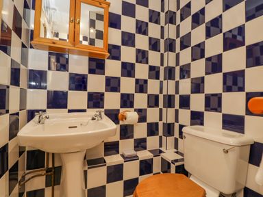 A bathroom with checkered black and white tiles a pedestal sink a wooden toilet seat and a wooden wall cabinet at Field Cottage in Shepton Mallet