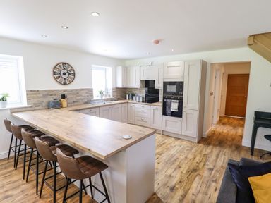 A kitchen with a wooden countertop and five bar stools at Lodge 24 in South Hykeham