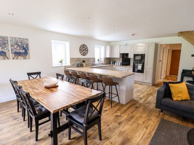 A kitchen with a wooden dining table and chairs a breakfast bar with stools and a sofa at Lodge 24 in South Hykeham