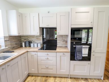 A kitchen with light cabinets wood countertop black appliances and a sink at Lodge 24 in South Hykeham