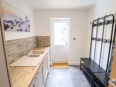 A utility room with a sink and wooden countertop and a black metal coat rack with benches at Lodge 24 in South Hykeham