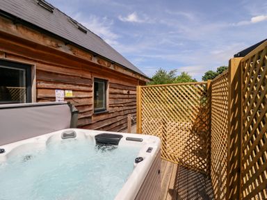 An outdoor hot tub next to a wooden building with lattice fencing around it at Lodge 24 in South Hykeham