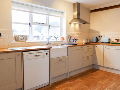 A kitchen with cabinets a dishwasher sink stove toaster kettle and a radio at The Brambles in Polstead