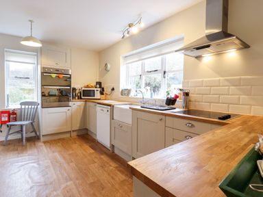 A kitchen with wooden countertops an oven a microwave a sink and a window at The Brambles in Polstead