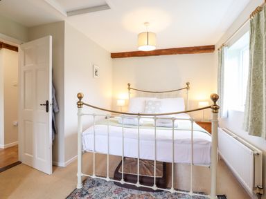 A bedroom with a metal bed frame bedside tables lamps and curtains at The Brambles in Polstead