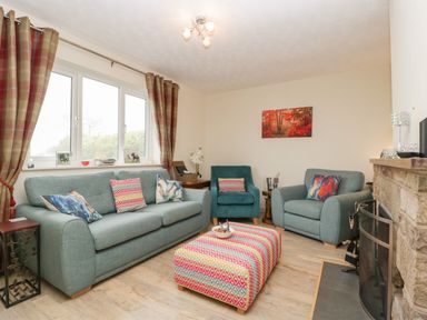 A living room with blue sofas a patterned ottoman a fireplace and plaid curtains at Palace Bungalow in St Weonards