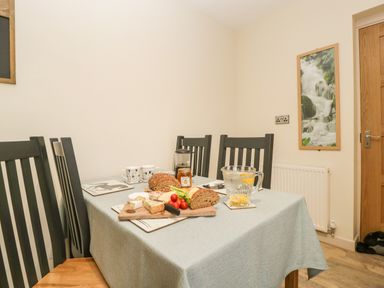 A dining table set with bread cheese cherry tomatoes and water in a room at Palace Bungalow in St Weonards