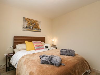 A bedroom with a bed and pillows a blanket and two folded robes on the bed at Palace Bungalow in St Weonards