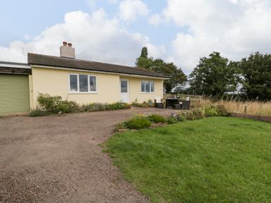 An exterior view of a bungalow with a gravel driveway a small garden and outdoor seating area at Palace Bungalow in St Weonards