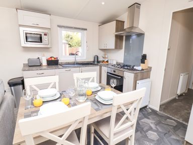 A kitchen with a dining table set with plates glasses and orange juice at Primrose Lodge in Runswick Bay near Staithes