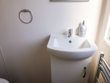 A bathroom sink with a chrome faucet soap dispenser and towel ring at Primrose Lodge in Runswick Bay near Staithes