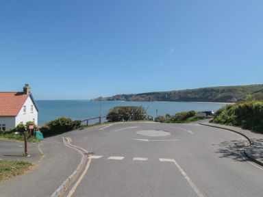 A view of the sea and cliffs with a house near the road at Primrose Lodge in Runswick Bay near Staithes