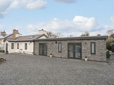 A modern single story house with stone and white walls and gravel driveway at Tan Y Coed - Nasareth in Nasareth near Penygroes