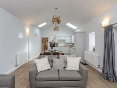 An open plan living room and kitchen with a sofa and dining table at Tan Y Coed - Nasareth Nasareth near Penygroes