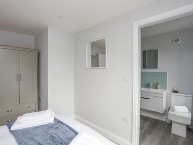 A bedroom with a wardrobe bed with blankets and leading to a bathroom with a sink and toilet at Tan Y Coed - Nasareth Nasareth near Penygroes