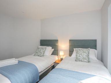 A bedroom with two single beds with blue headboards a bedside lamp and blue blankets at Tan Y Coed - Nasareth in Nasareth near Penygroes