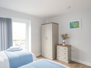 A bedroom with two single beds a wardrobe a chest of drawers and a framed map on the wall at Tan Y Coed - Nasareth Nasareth near Penygroes