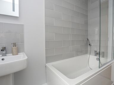 A bathroom with a bathtub and a sink with a soap dispenser at Tan Y Coed - Nasareth in Nasareth near Penygroes