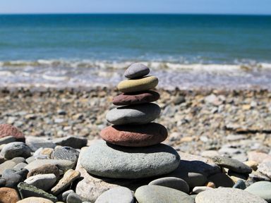 A stack of smooth stones on a pebble beach with the sea and sky in the background at Tan Y Coed - Nasareth Nasareth near Penygroes