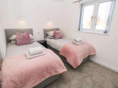 A bedroom with two single beds pink blankets and pillows and window at Harry's Lodge in Ashover