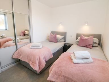 A bedroom with two single beds pink blankets and pillows at Harry's Lodge in Ashover