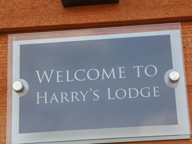 A sign reading welcome to Harrys Lodge mounted on a wooden surface at Harry's Lodge in Ashover