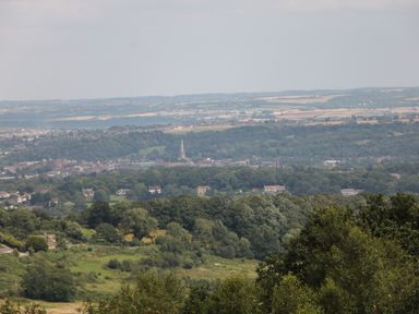 A landscape view of a town with a church spire surrounded by trees and fields at Harry's Lodge in Ashover