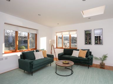 A living room with two green sofas and a round wooden coffee table at Ynys Faelog Cottage in Ynys Faelog near Menai Bridge