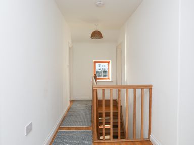 A hallway with wooden stairs and two doors on either side at Ynys Faelog Cottage in Ynys Faelog near Menai Bridge