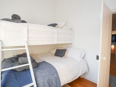 A bedroom with a white bunk bed and folded towels on the bottom bed at Ynys Faelog Cottage in Ynys Faelog near Menai Bridge